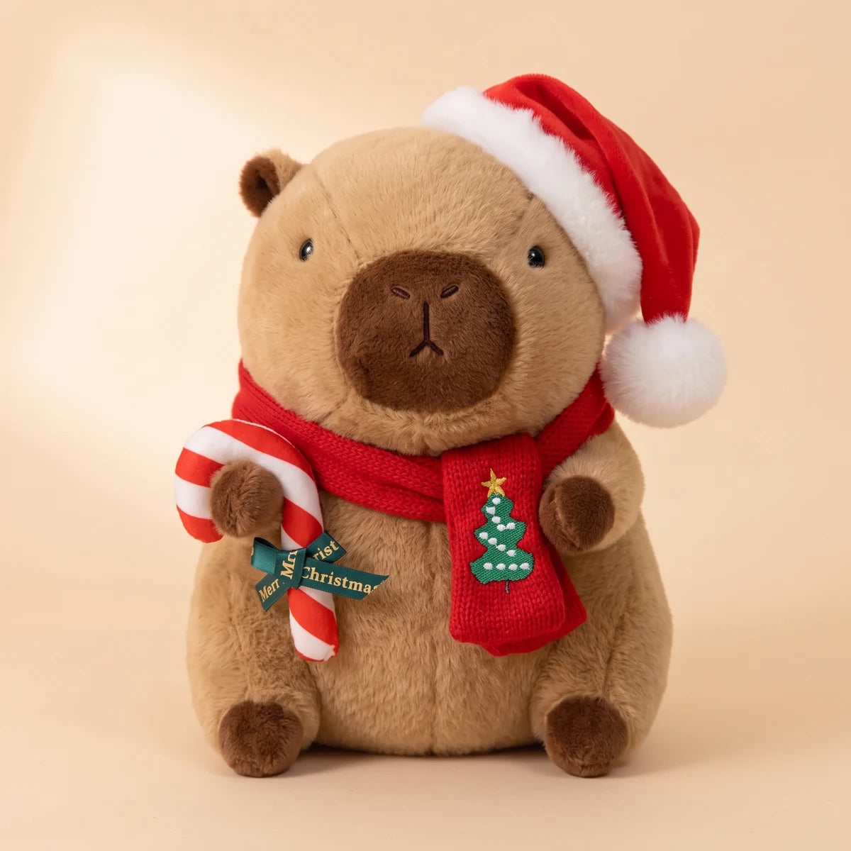 Front view of the Christmas capybara plush with a Santa hat holding a candy cane