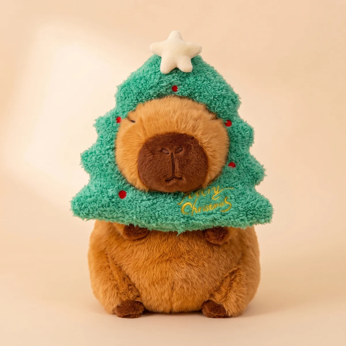 Front view of the capybara plush wearing a green Christmas tree hood with a star
