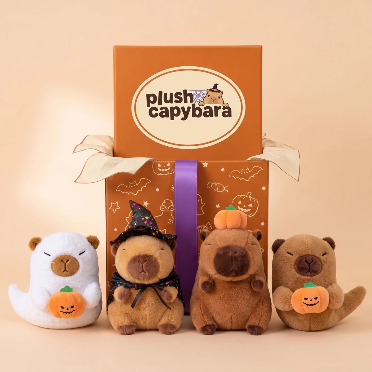 Front view of the four Halloween capybara plush lined up on a peach studio backdrop