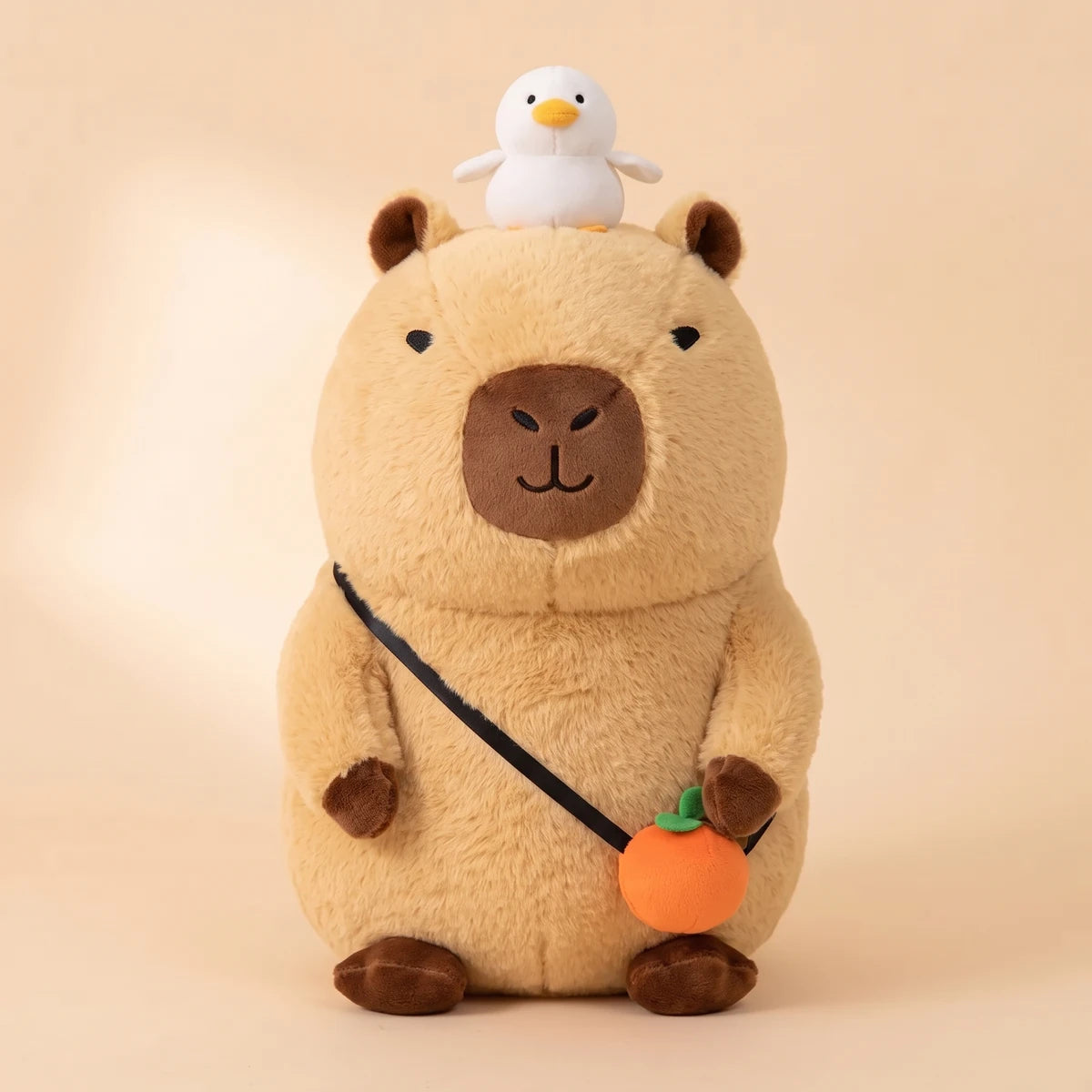Front view of the capybara plush with a white bird on its head and an orange bag
