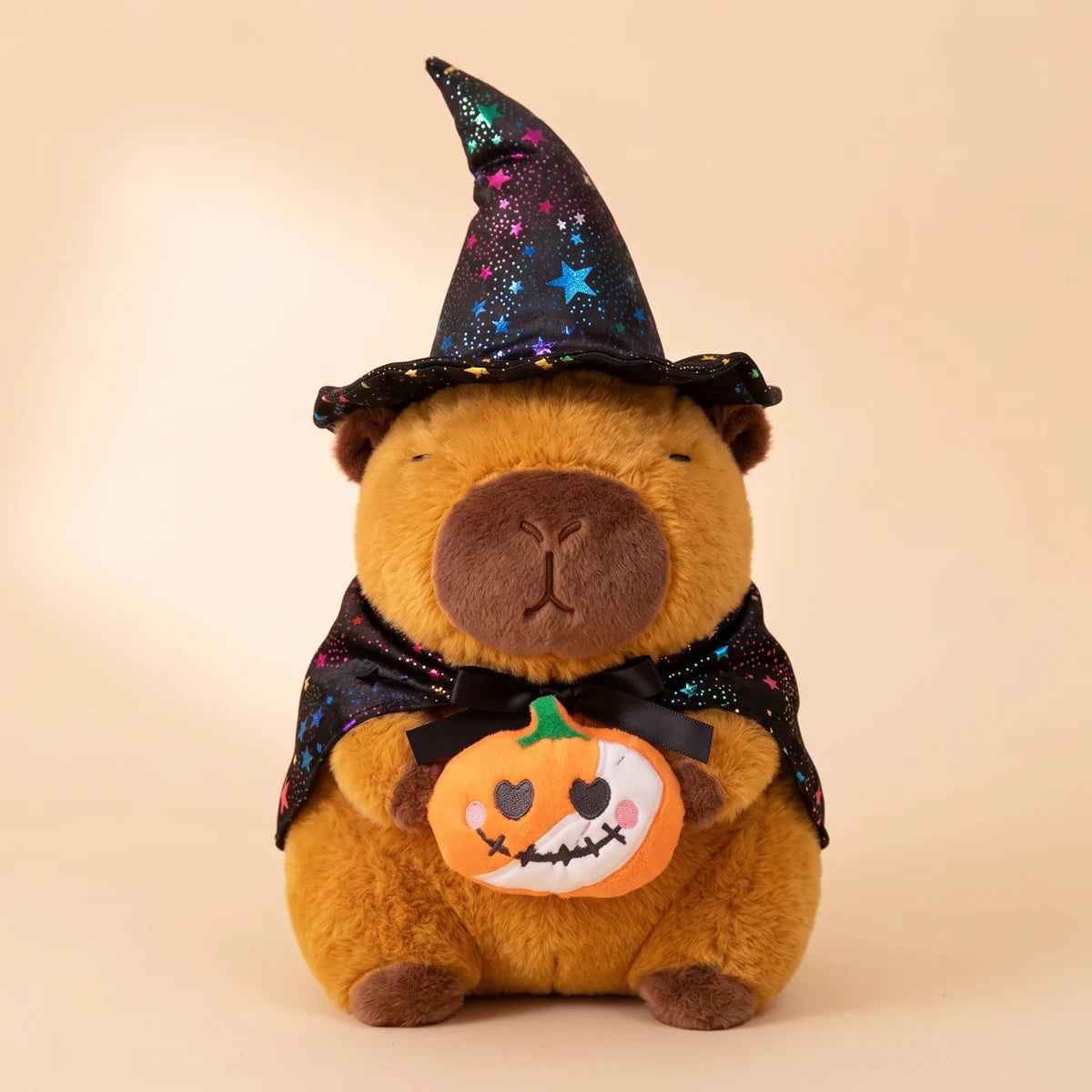 Front view of the pumpkin witch capybara plush holding a small orange pumpkin