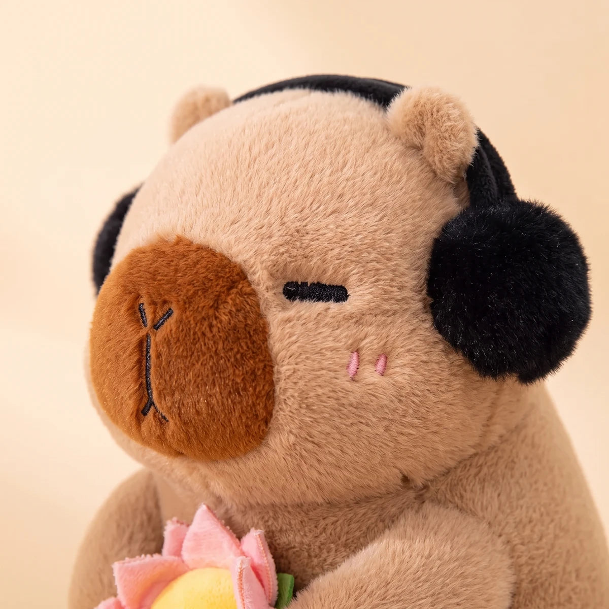 Close-up of the brown capybara plush face with fluffy black headphones