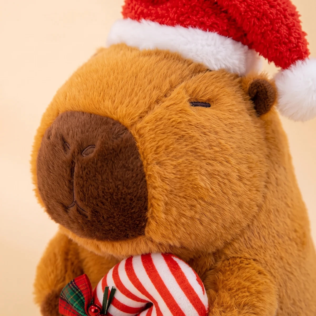 Close-up of the face of the Christmas capybara plush with its red Santa hat