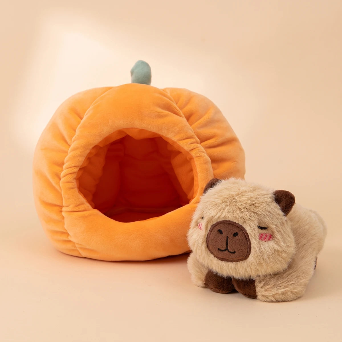 Pumpkin house capybara plush set shown as two pieces, the capybara lying beside the house
