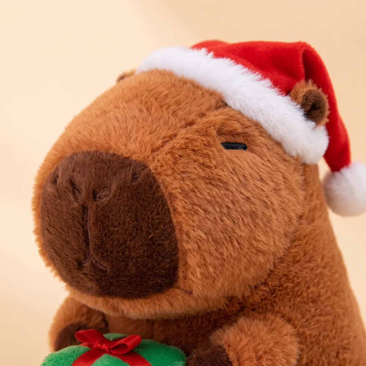 Close-up of the capybara plush face under its red Santa hat