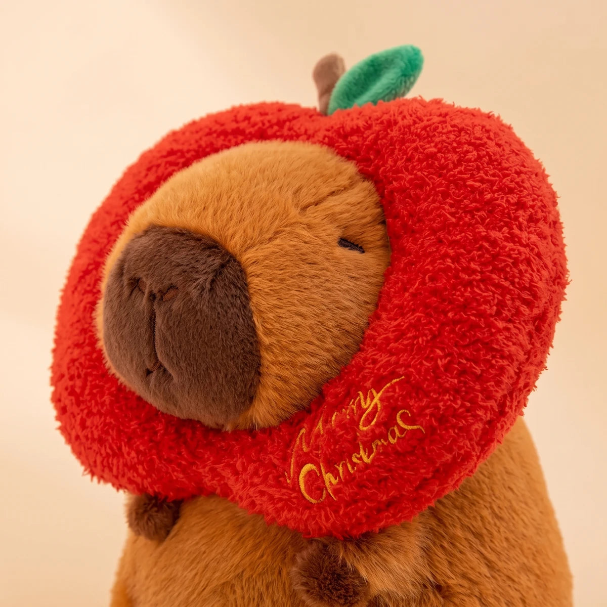 Close-up of the Christmas apple capybara plush with the Merry Christmas embroidery
