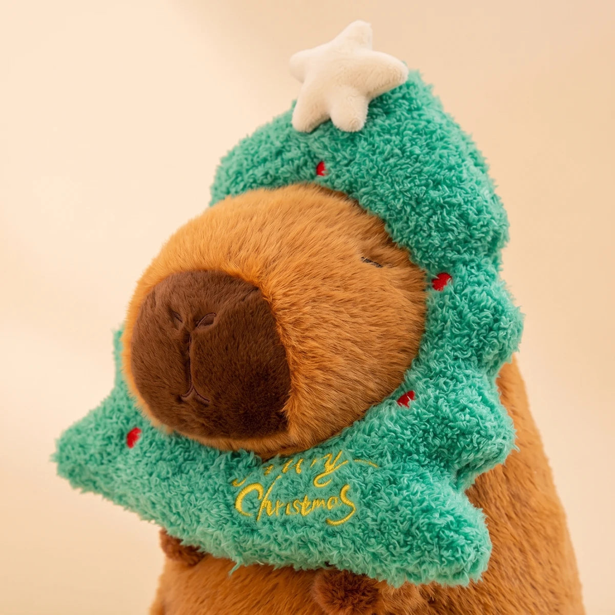 Close-up of the Christmas tree capybara plush with the Merry Christmas embroidery