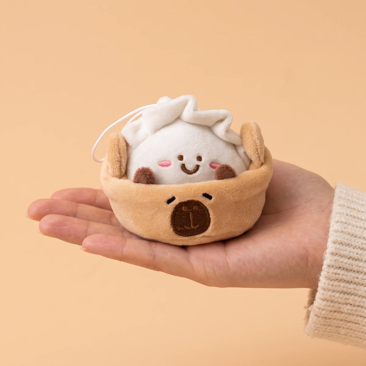 Dumpling capybara keychain resting in an open palm to show its 3 in size