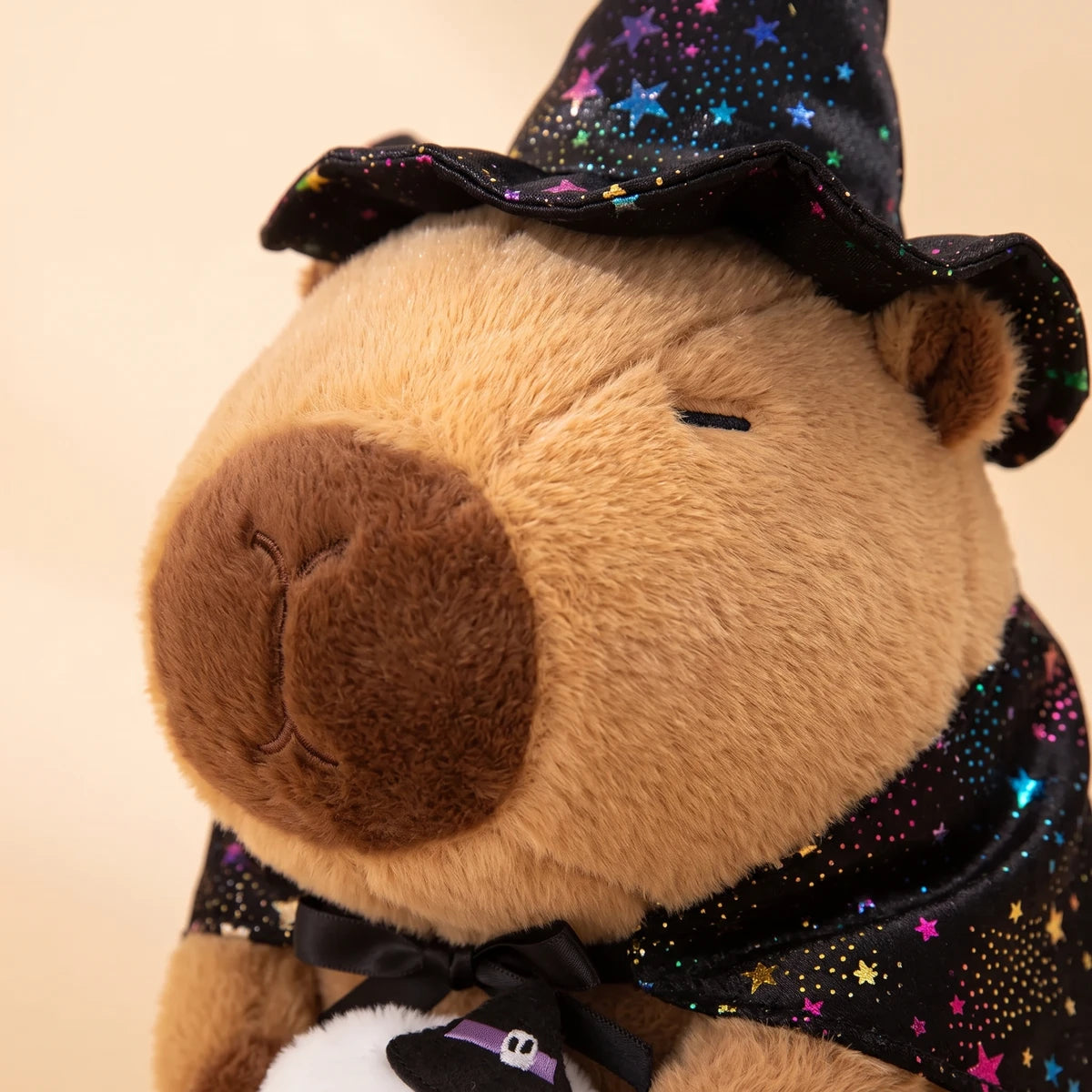 Close-up of the face of the ghost witch capybara plush under its starry witch hat