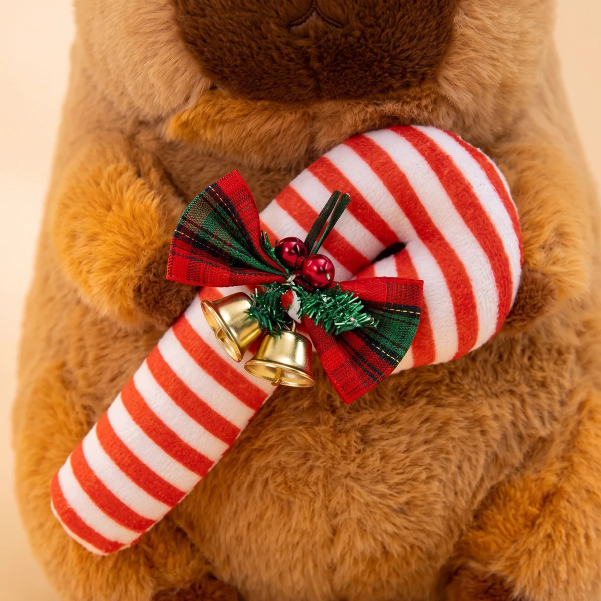 Close-up of the plush candy cane with its plaid bow and two gold jingle bells