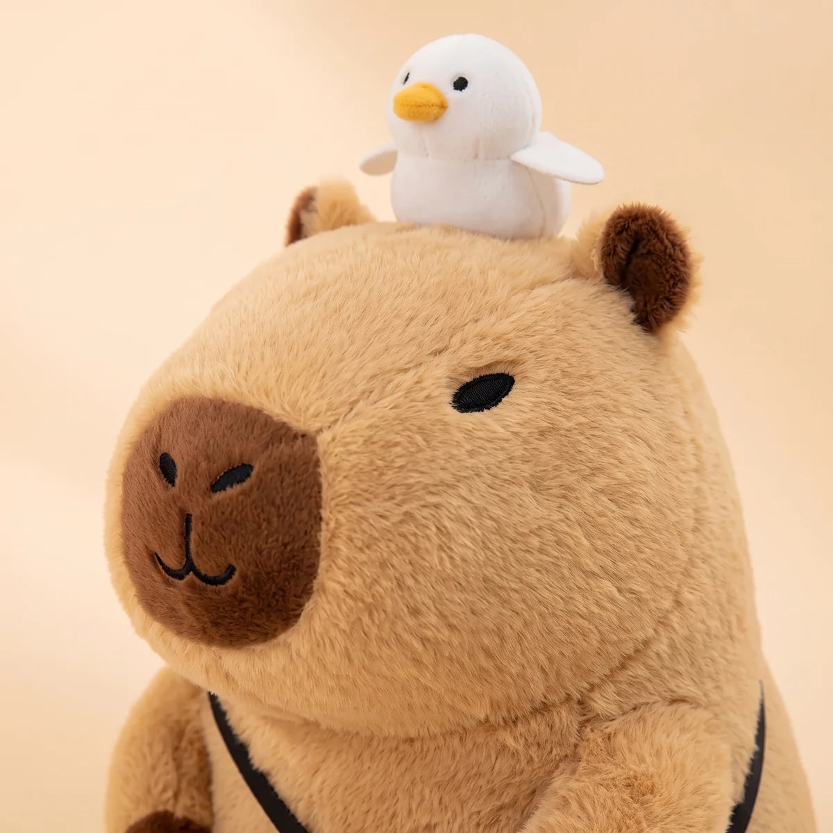 Close-up of the capybara plush face with the white bird on its head