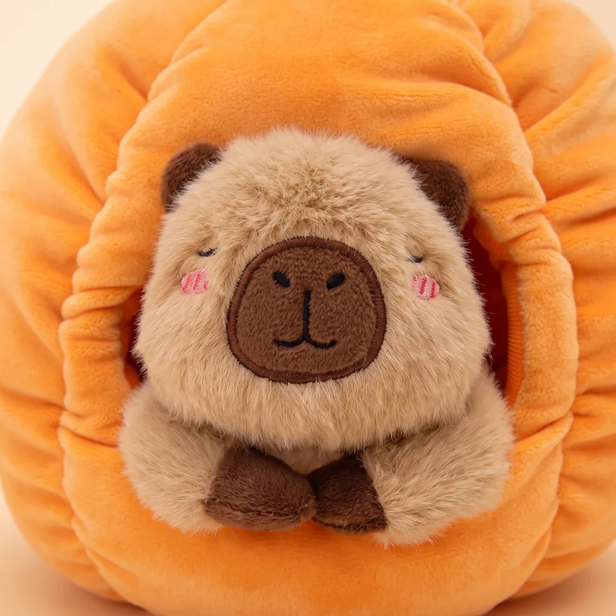Close-up of the capybara face framed by the opening of the pumpkin house capybara plush set