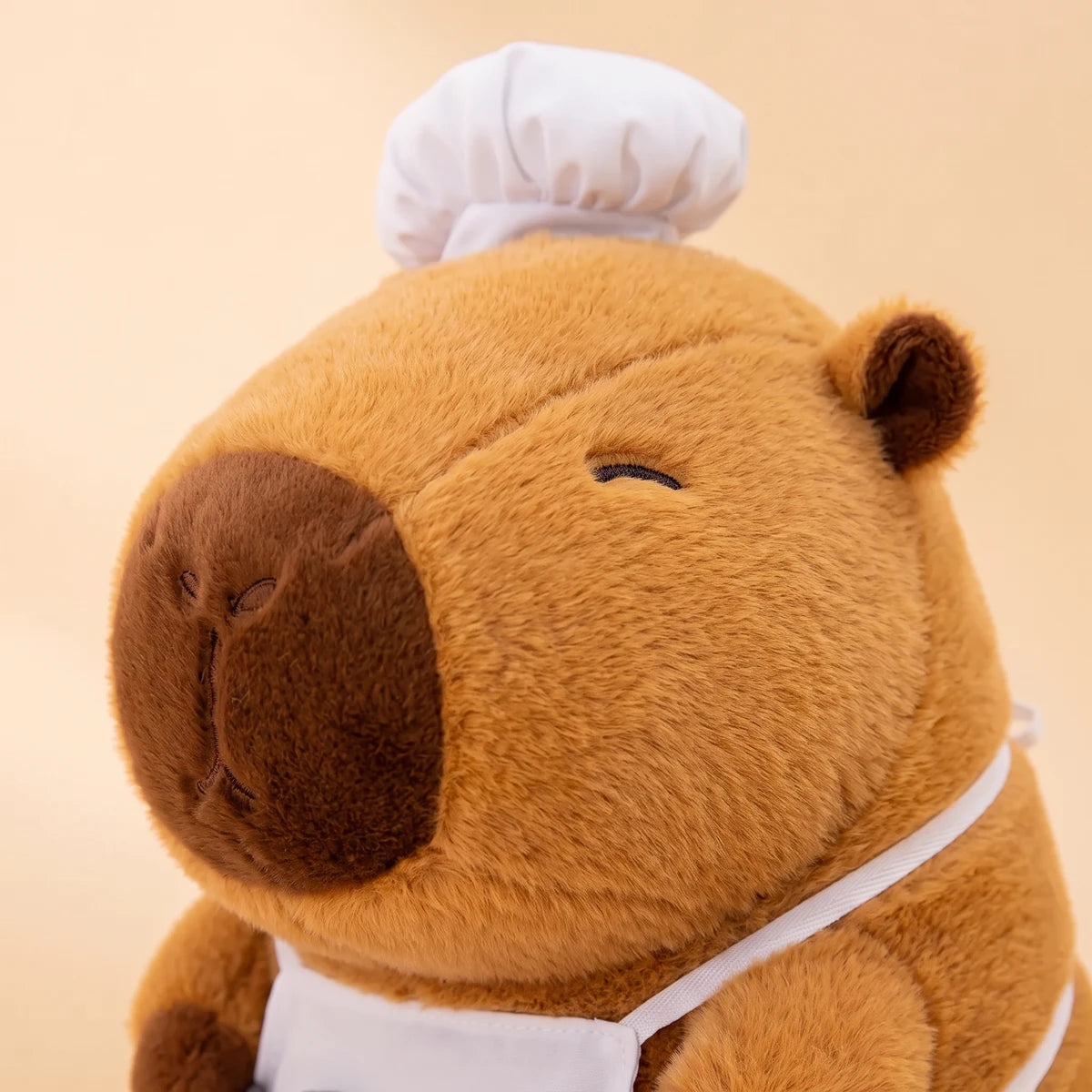 Close-up of the ramen chef capybara plush face under its white chef hat
