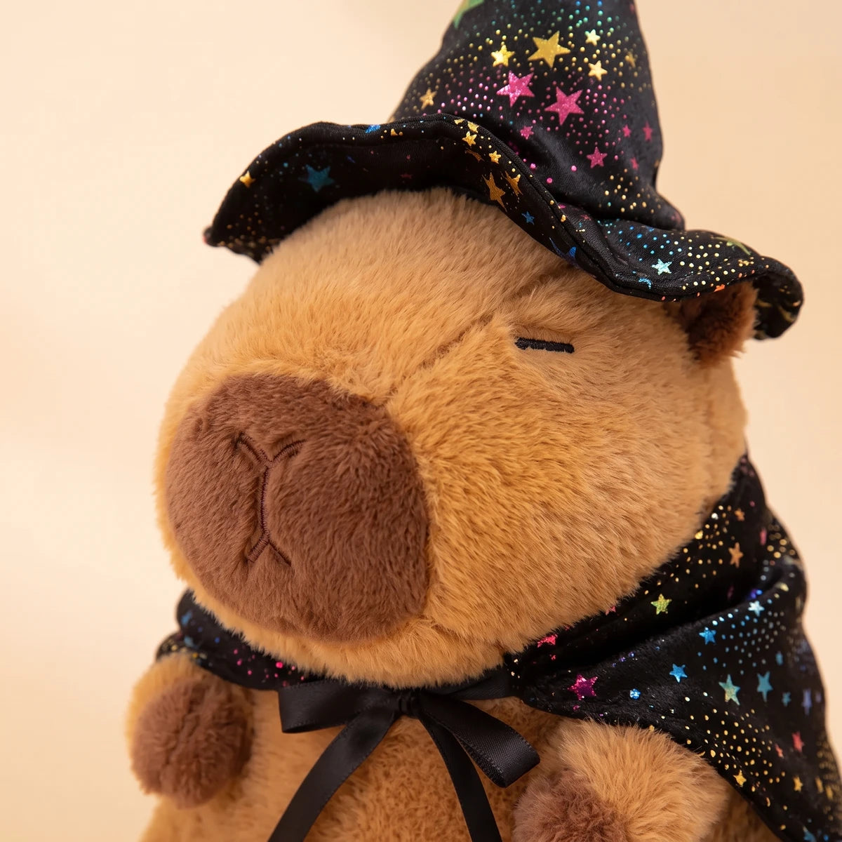Close-up of the face of the witch capybara plush under its starry witch hat