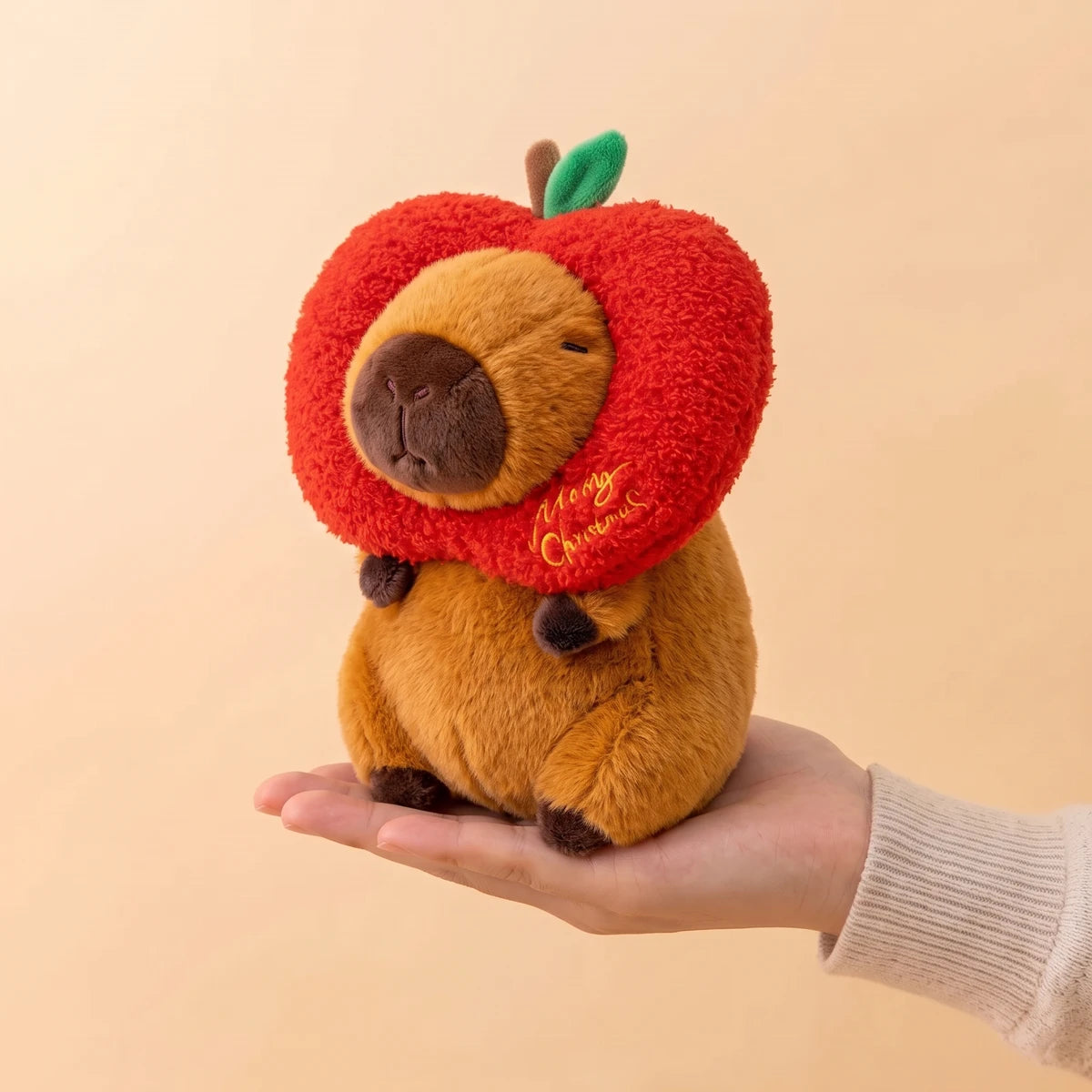 8 in Christmas apple capybara plush sitting on an open hand
