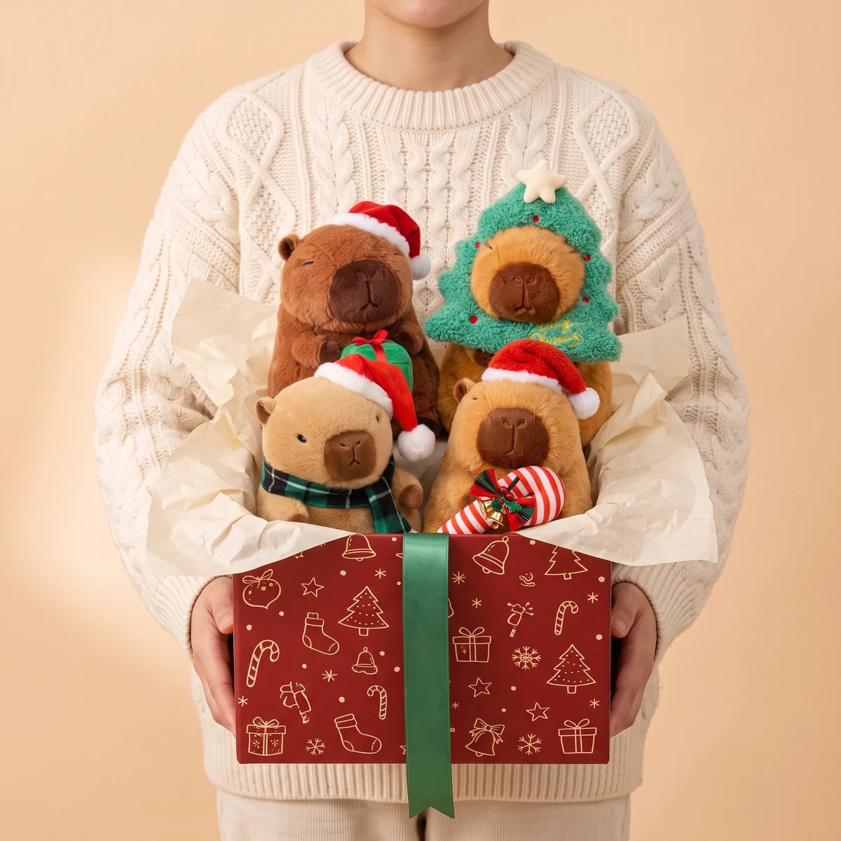Person in a cream cable knit sweater holding the four Christmas capybara plush