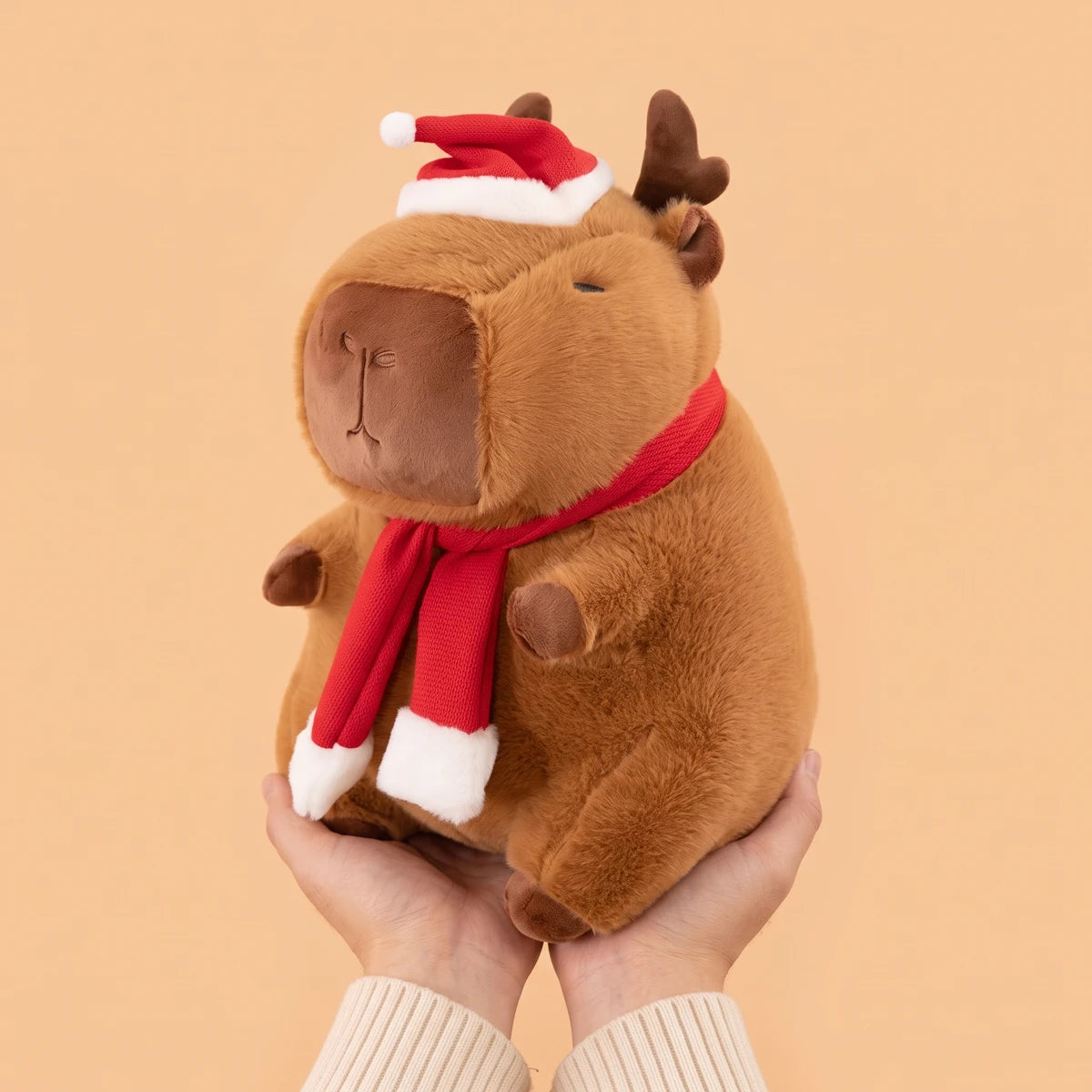 Reindeer capybara plush held in two hands to show its 12 in size