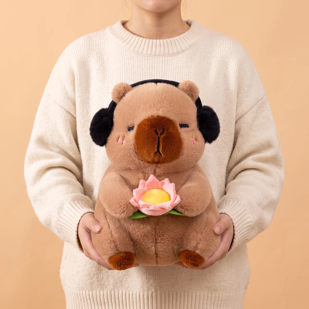 Person holding the 15 in brown headphones capybara plush