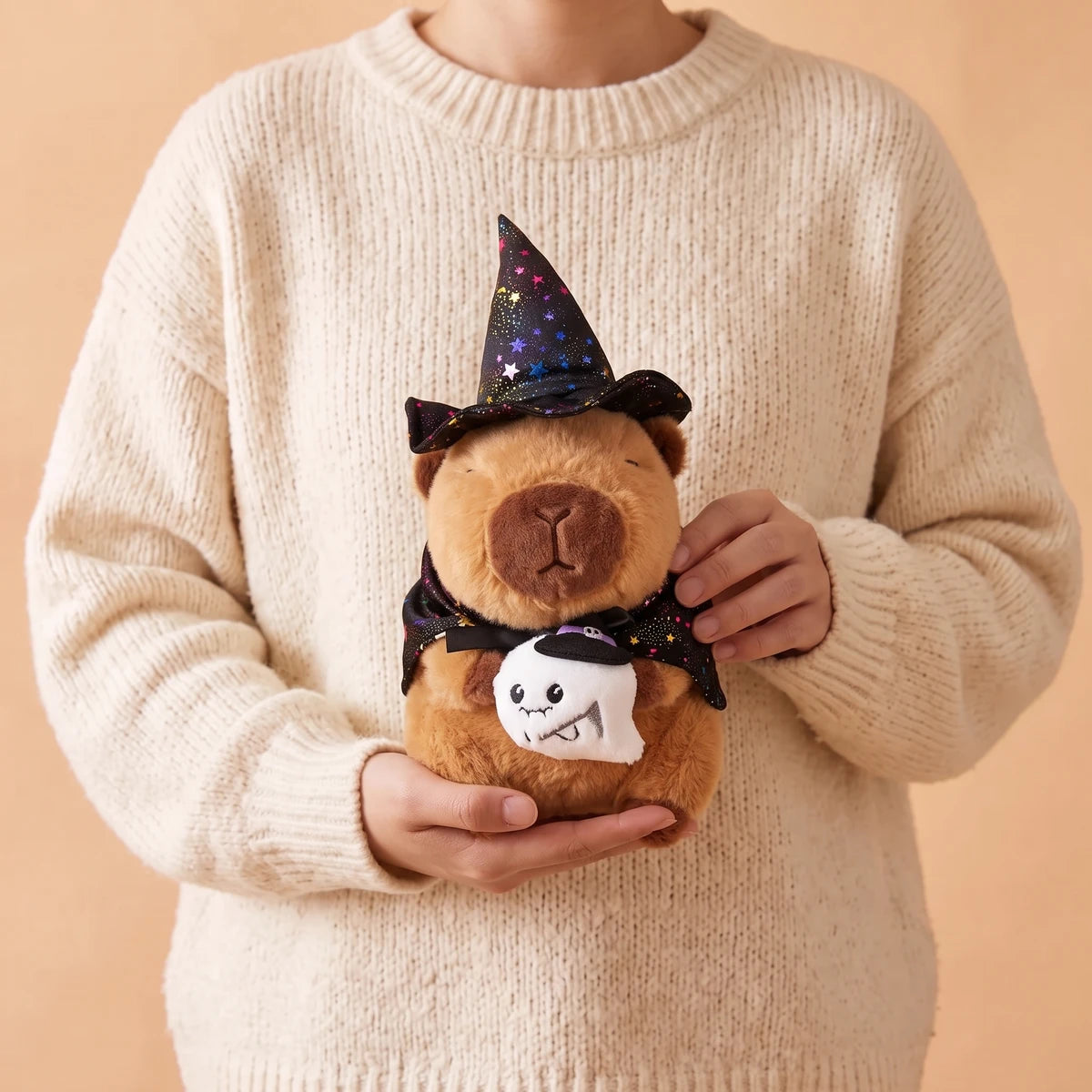 Person in a cream sweater holding the ghost witch capybara plush