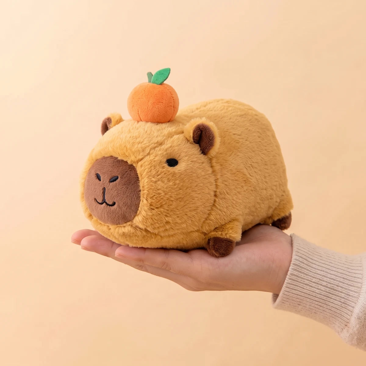 8 in lying capybara plush resting on an open hand