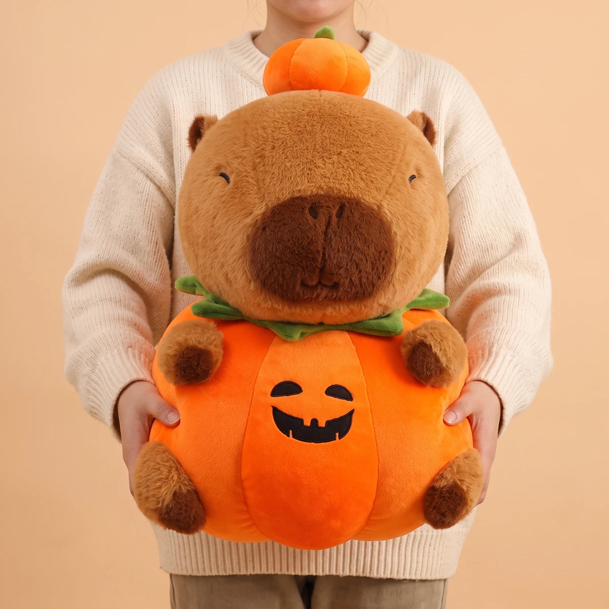 Person holding the 24 in pumpkin capybara plush in front of their chest
