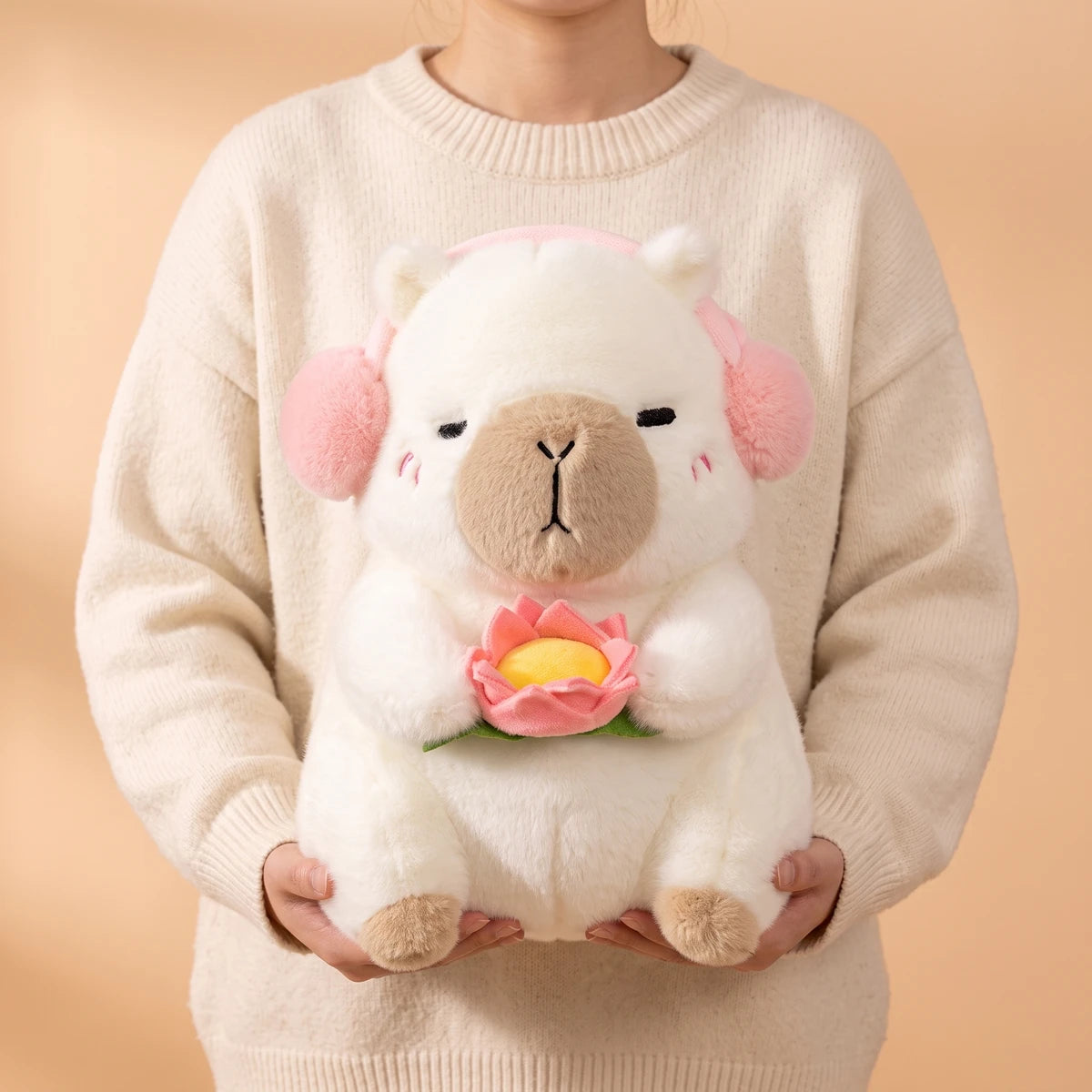 Person holding the 15 in white headphones capybara plush