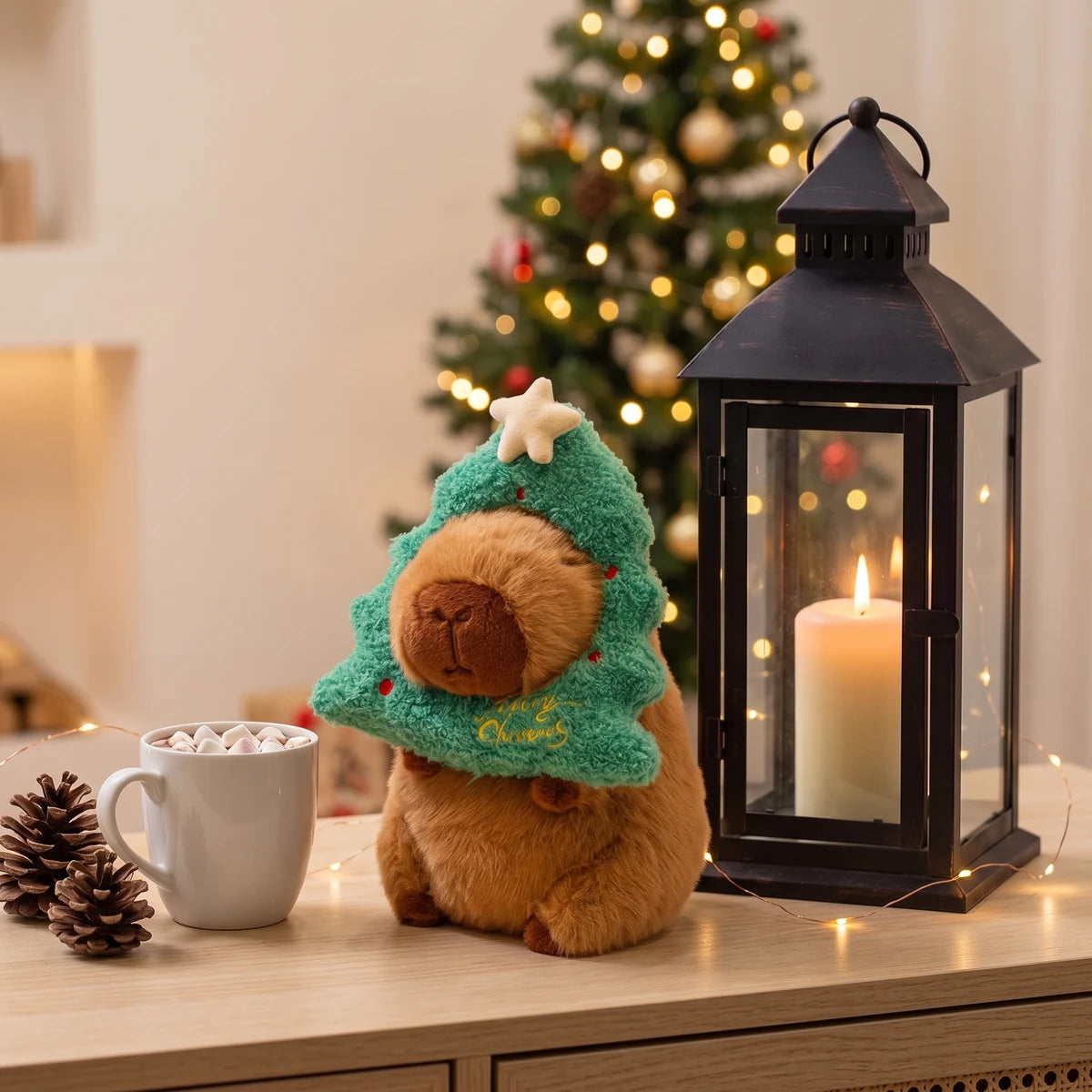 Christmas tree capybara plush on a console next to a lantern and a mug of hot chocolate