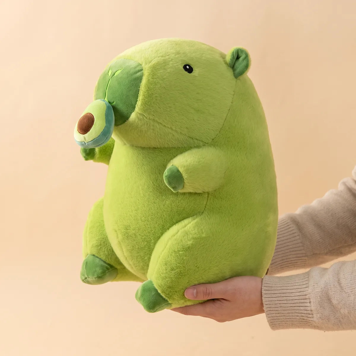 Avocado capybara plush balanced side on across one open hand