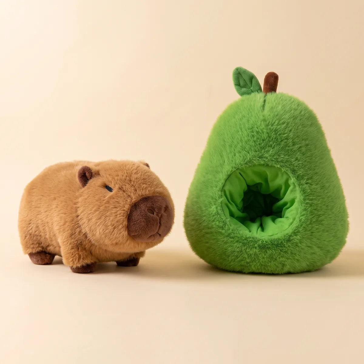 Avocado house capybara plush set photographed side by side, the standing brown capybara next to the open green avocado