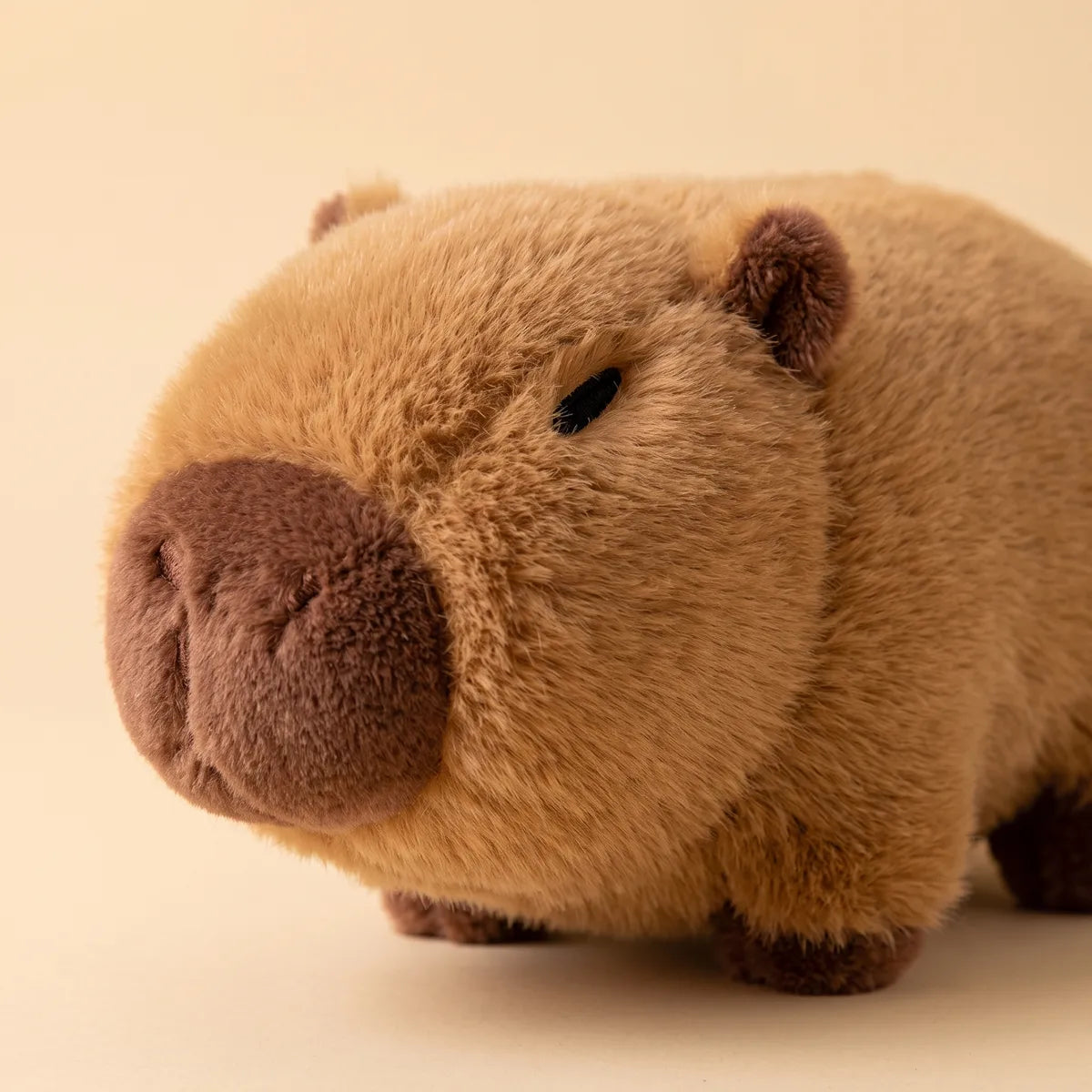 Close-up of the brown capybara from the avocado house plush set showing its dark chocolate snout and stitched eye