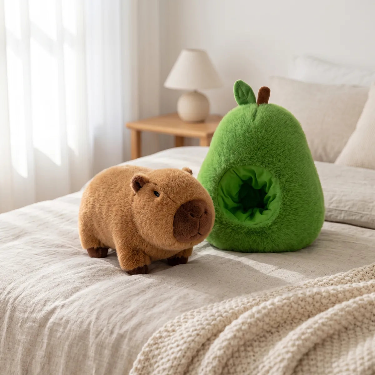 Avocado house capybara plush set arranged on a bed, the brown capybara standing beside the green avocado shell