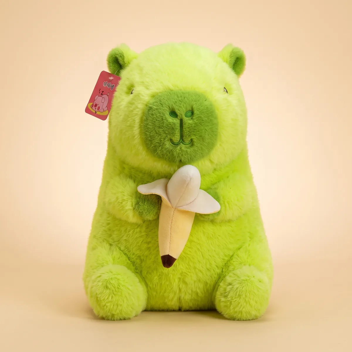 Front view of the 9 in banana capybara plush sitting upright with its plush banana