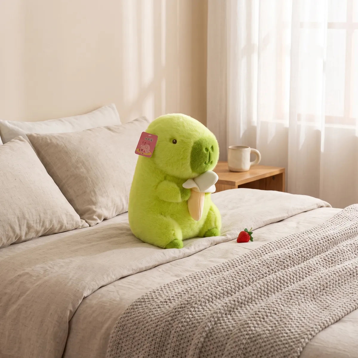 Green banana capybara plush sitting on a made bed with linen bedding