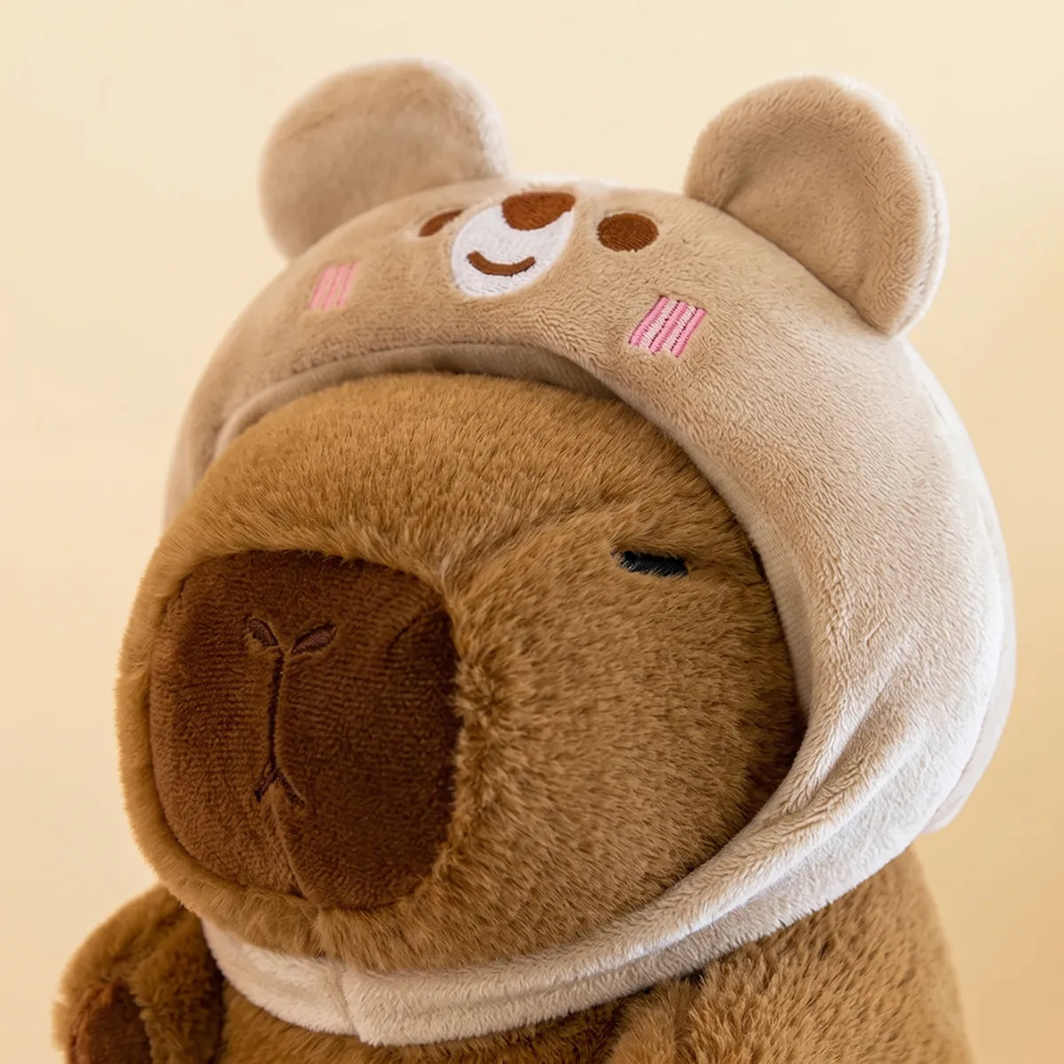 Close up of the embroidered bear face on the hood of the capybara plush