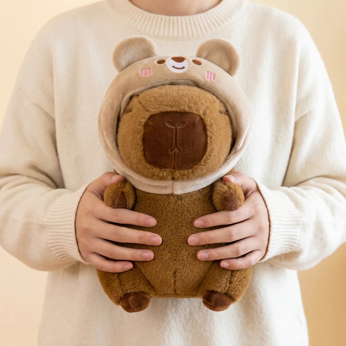 Person hugging the bear capybara plush against a knit sweater