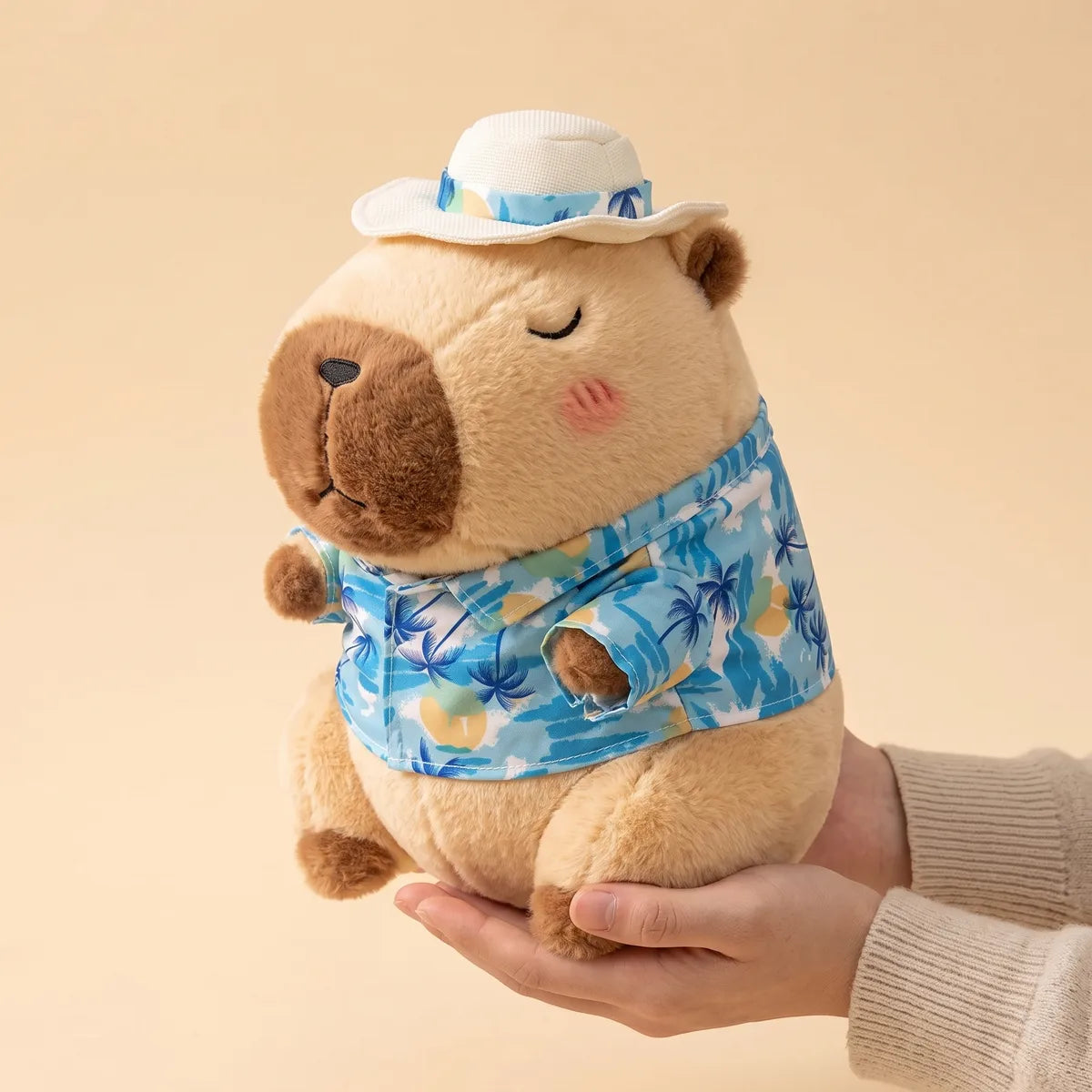 Brown capybara stuffed animal held in one open hand to show its 12 in seated height