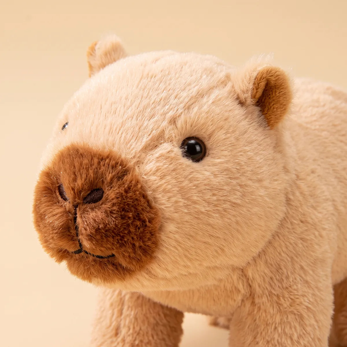 Close-up of the brown walking capybara toy showing its chestnut snout, glossy open eye and rounded ear