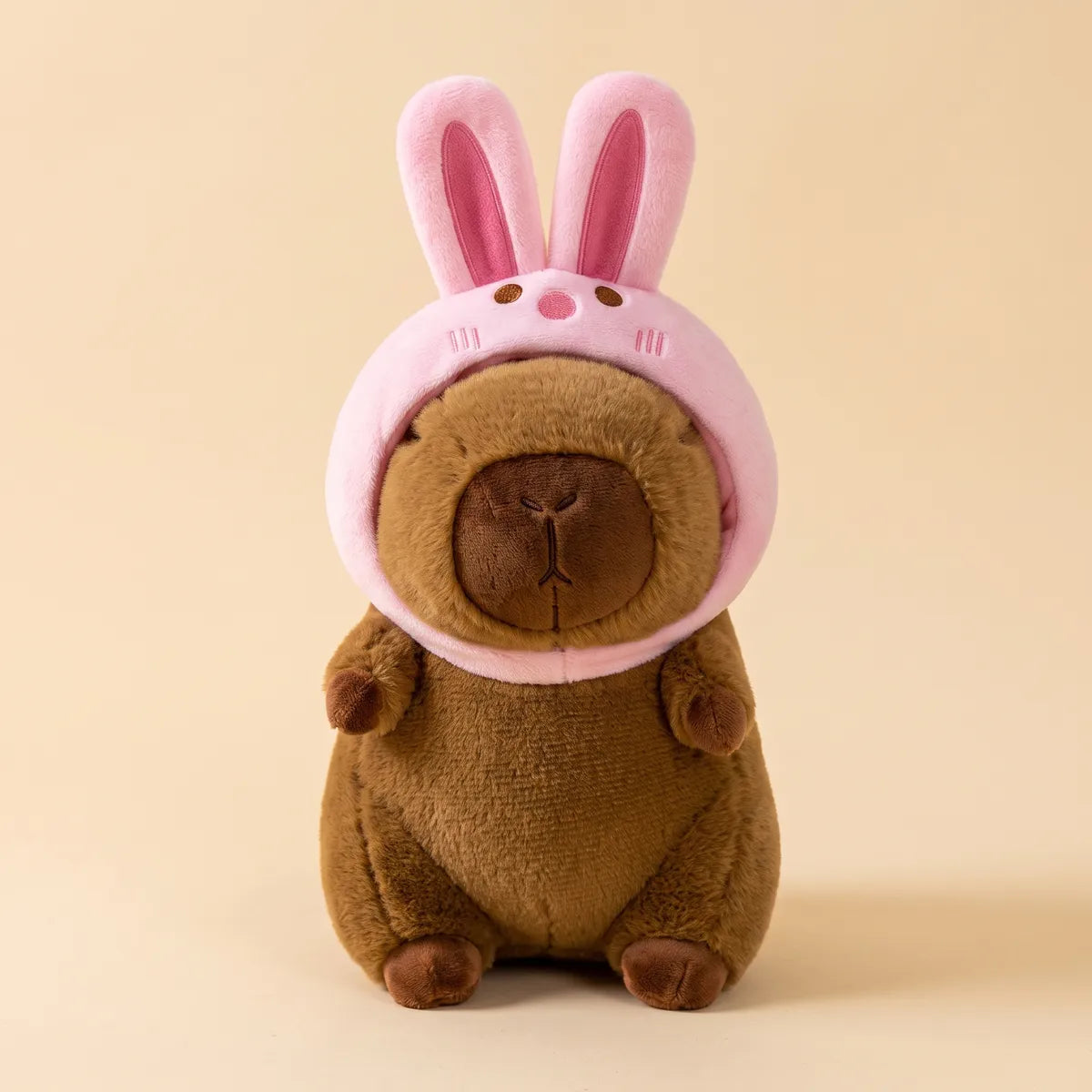 Brown bunny capybara plush seen from the front in its pink rabbit hood
