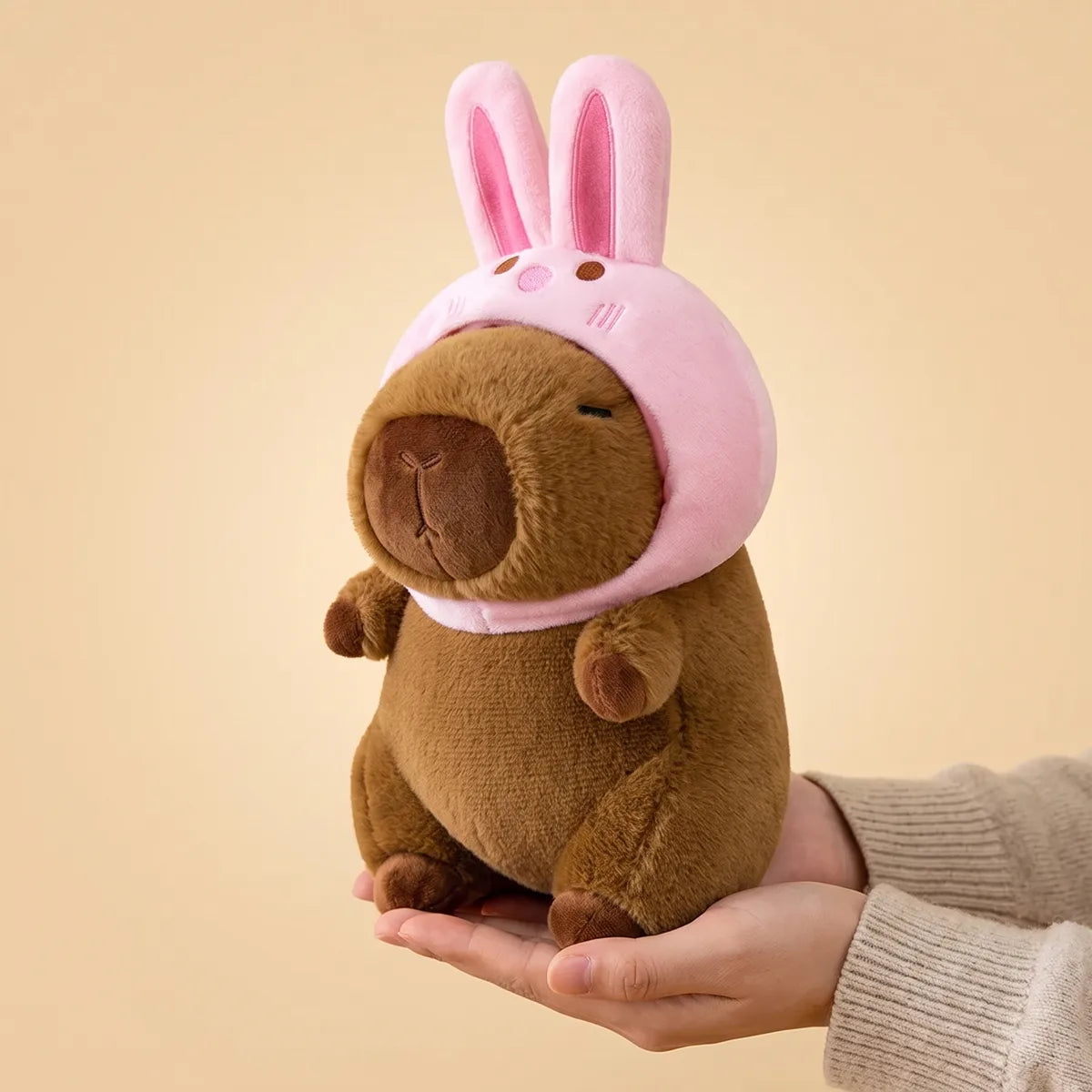 Hands cradling the 9 in (22 cm) bunny capybara plush to show its real size