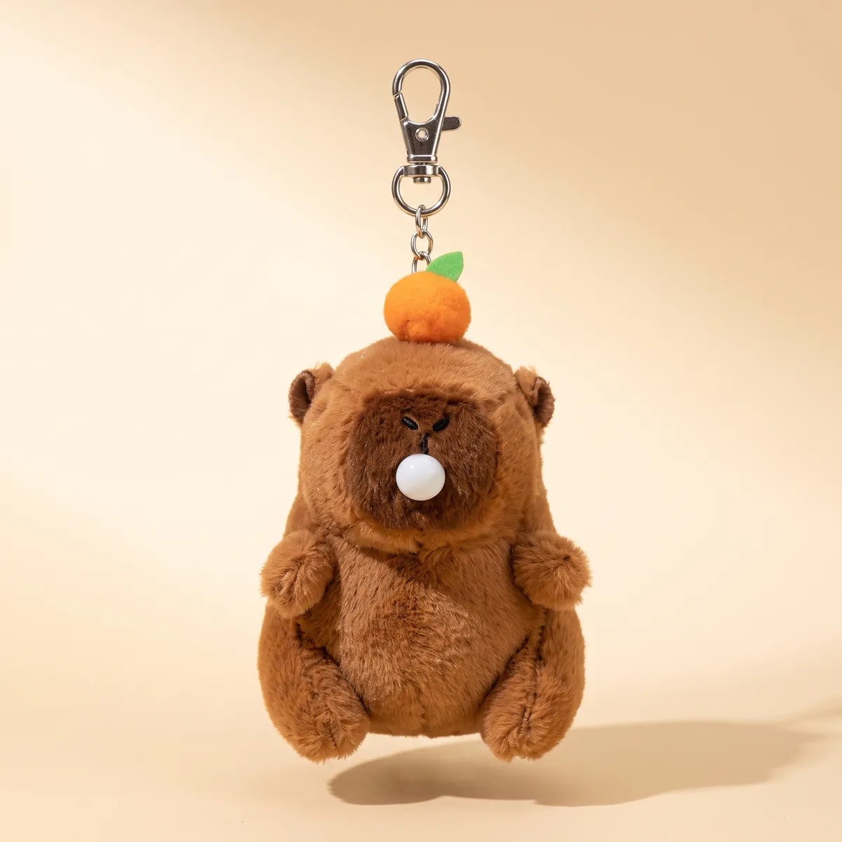 Brown capybara blowing bubble keychain plush hanging front on from a silver clasp, white bubble at its muzzle.