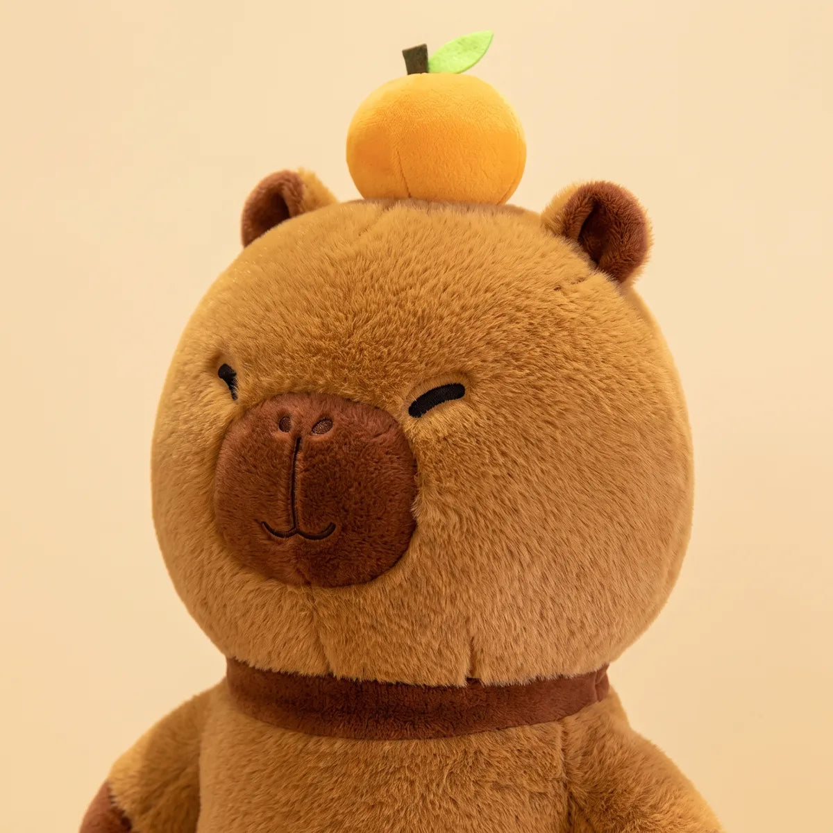 Close up of the head and the small citrus on the capybara body pillow plush