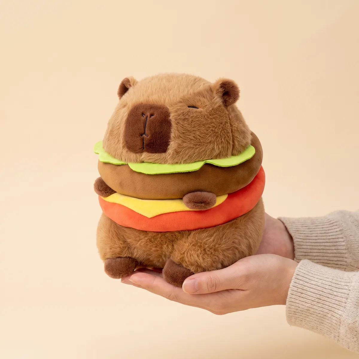 Hands cradling the capybara burger plush to show its real size