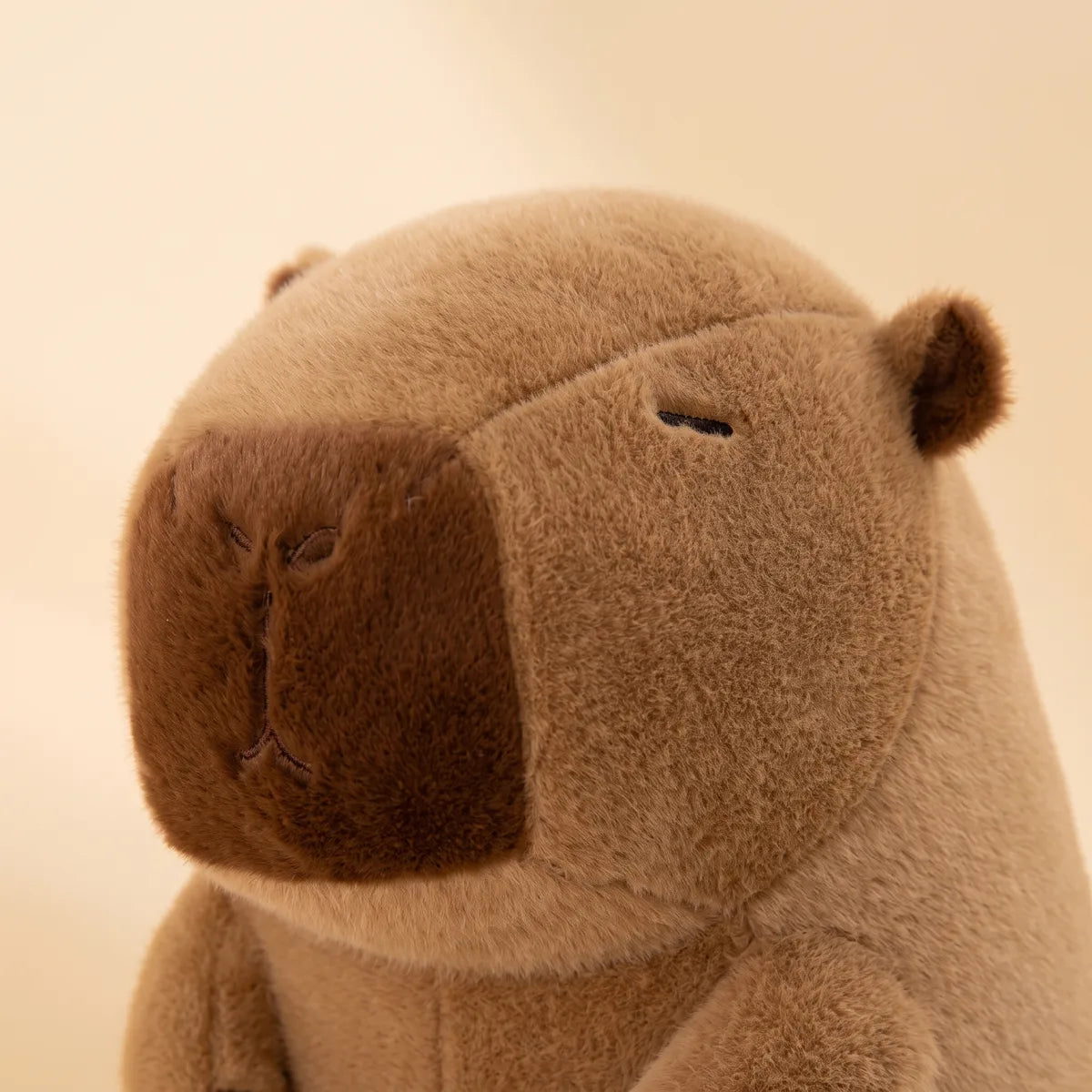 Close up of the capybara drinking boba plush head showing the dark brown muzzle panel and single stitched eye.