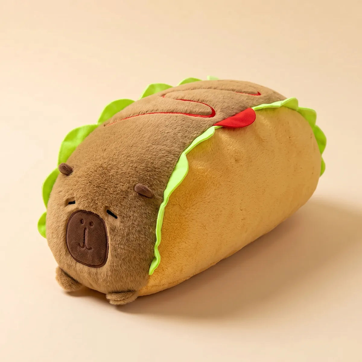 Angled studio view of the capybara hot dog plush, brown capybara body lying in a golden bun with a green lettuce frill