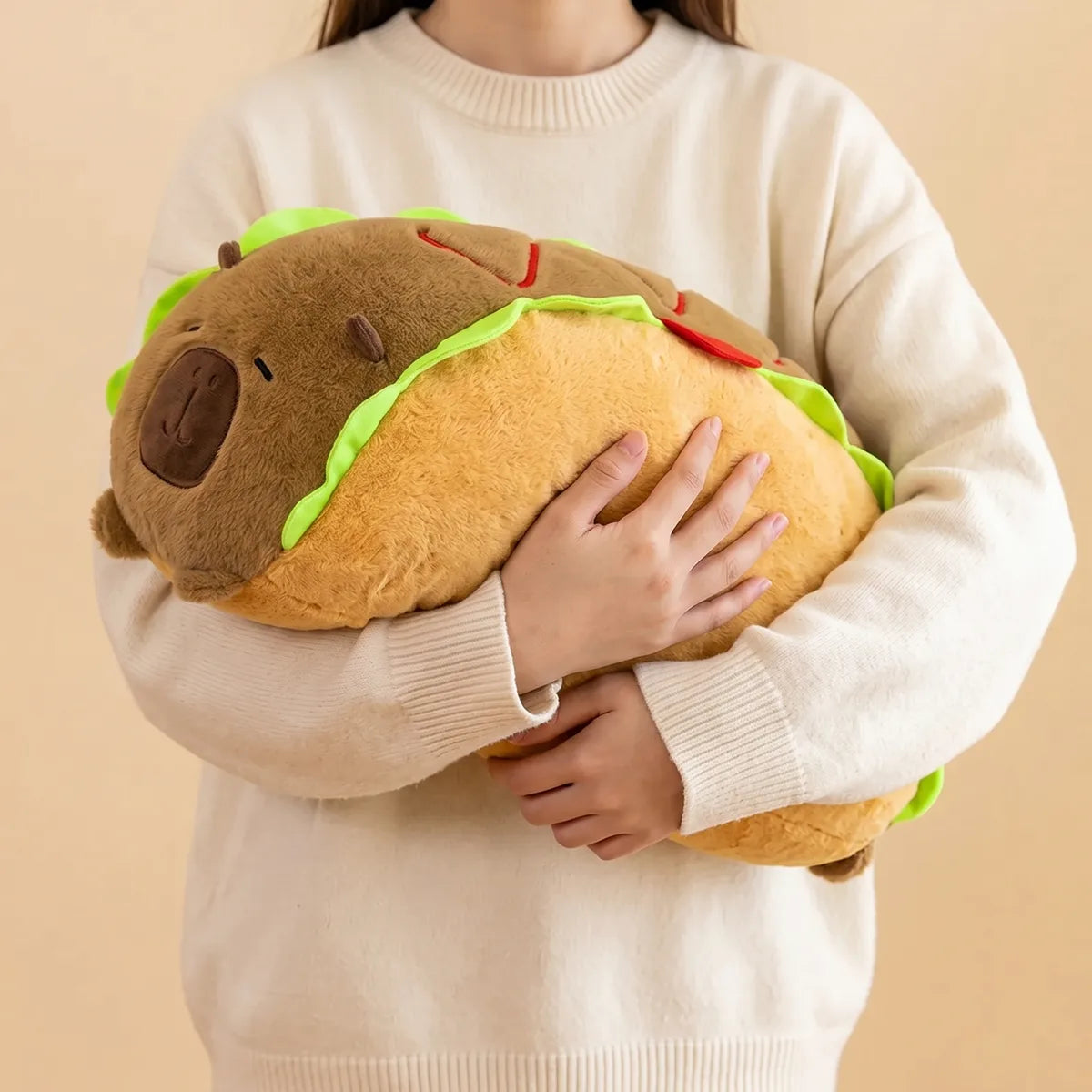 Person holding the capybara hot dog plush in both arms, showing the 20 in length across the chest
