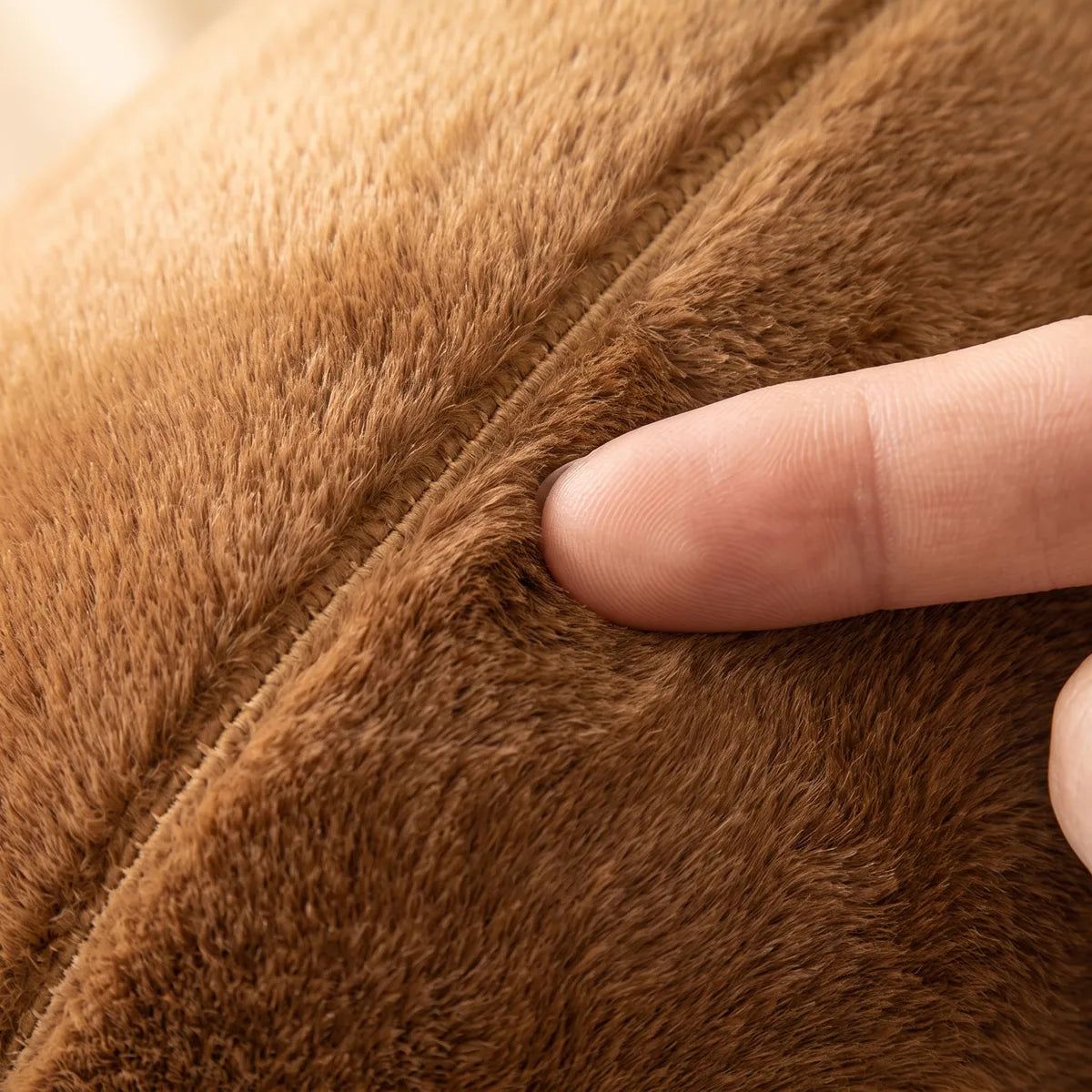 Fingertip pressing into the dense caramel brown pile of the capybara snot plush