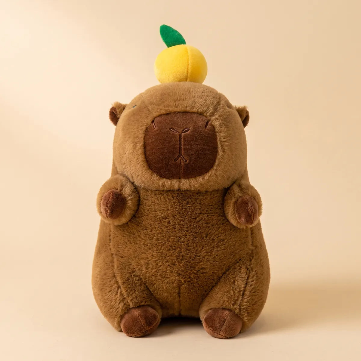 Front view of the brown capybara with orange on head plush, the citrus and green leaf sitting on its head