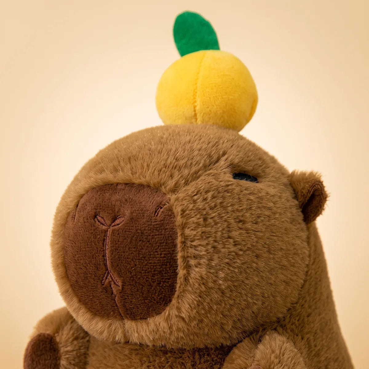 Close up of the citrus and green leaf sewn into the crown of the capybara with orange on head plush