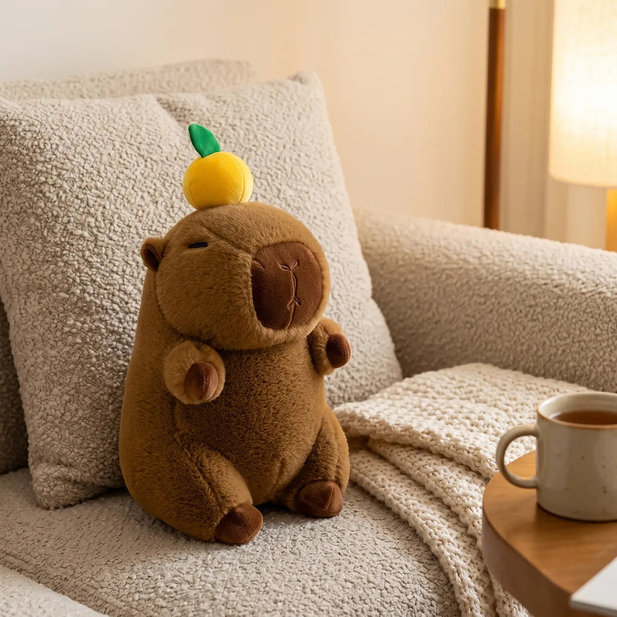 Capybara with orange on head plush placed in a bright home setting with the fruit facing the camera