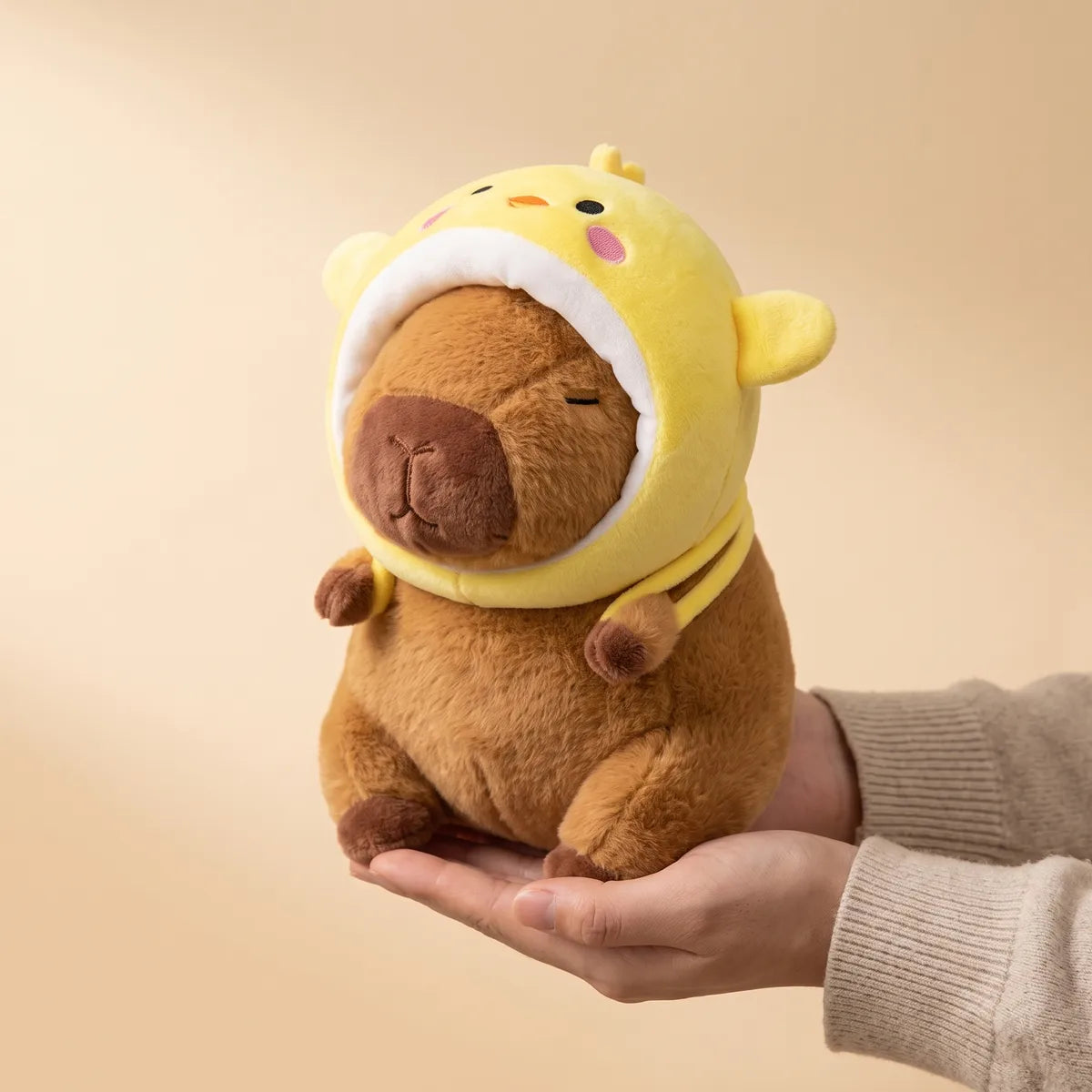 Hands cradling the chicken capybara plush to show its real size